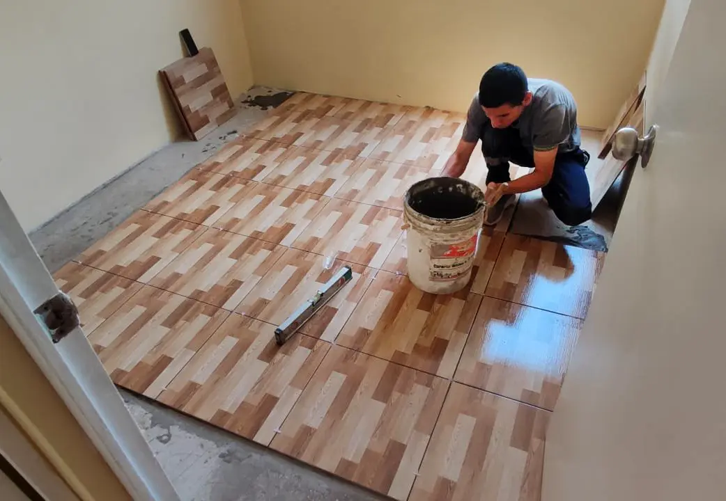 Instalador de mayolica colocando piso tipo madera