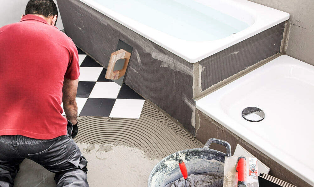 Trabajador instalando porcelanato en baño - Servicio profesional Lima